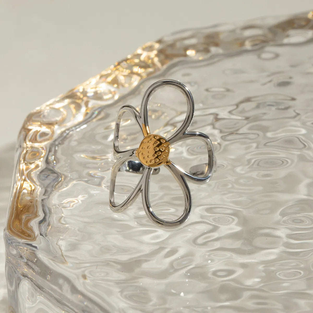 Anel margarida bicolor prateado com centro dourado em design delicado sobre superfície texturizada