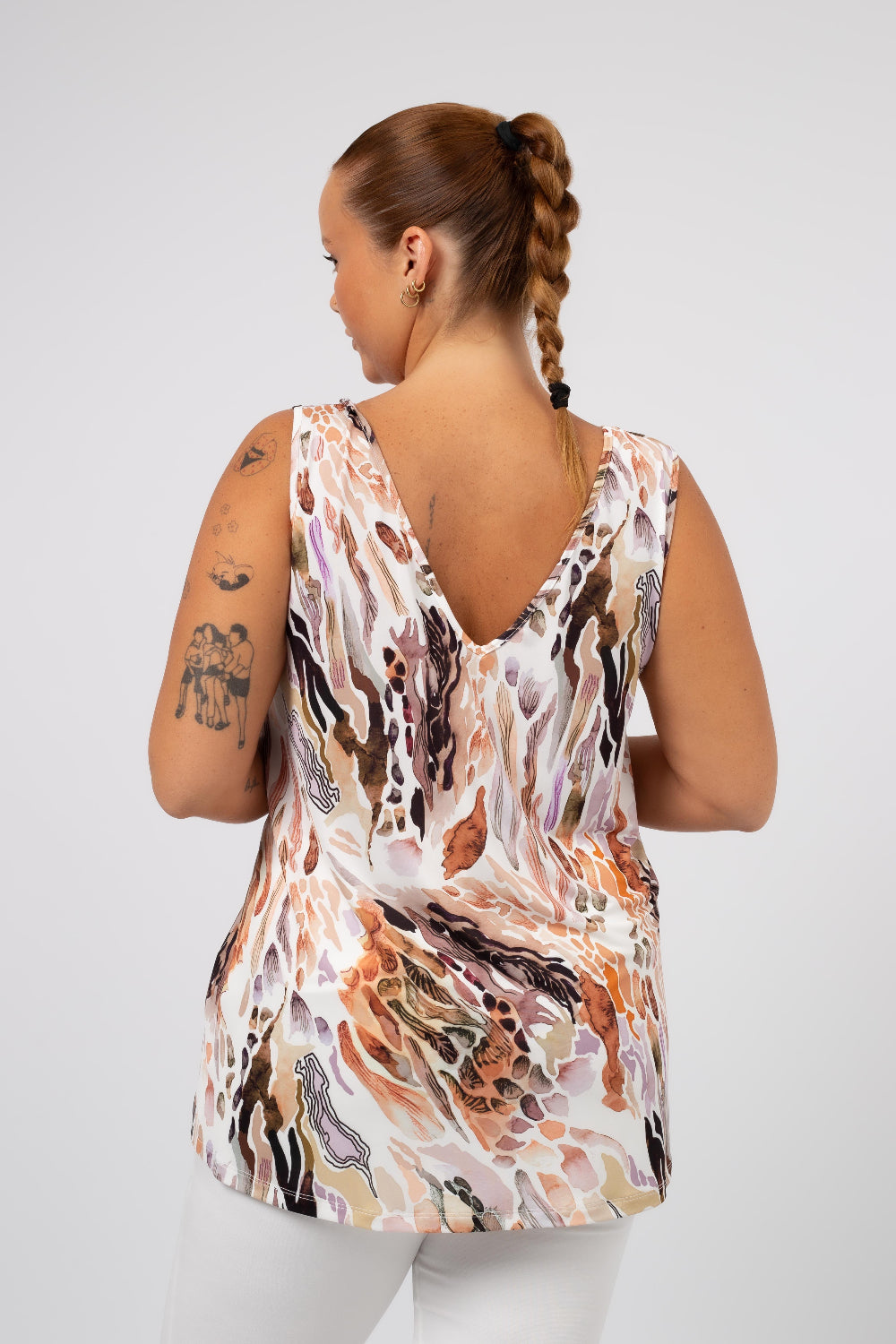 Mulher usando blusa com abstrato tons terrosos sem mangas com decote nas costas da Curvy