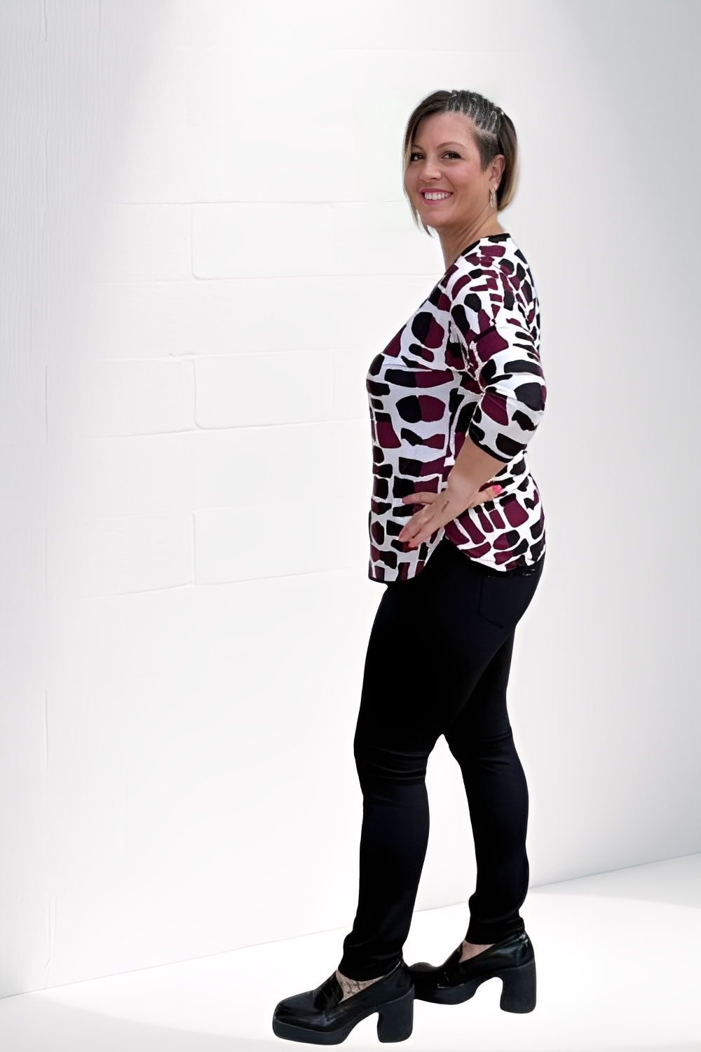 Mulher usando blusa estampa paisley da Alma com calça preta e sapatos de salto preto