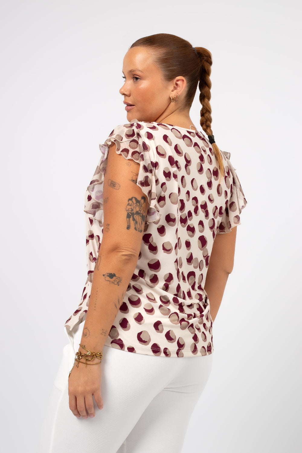 Mulher usando blusa estampada tamanho grande Curvy com estampa de bolinhas roxas e mangas franzidas