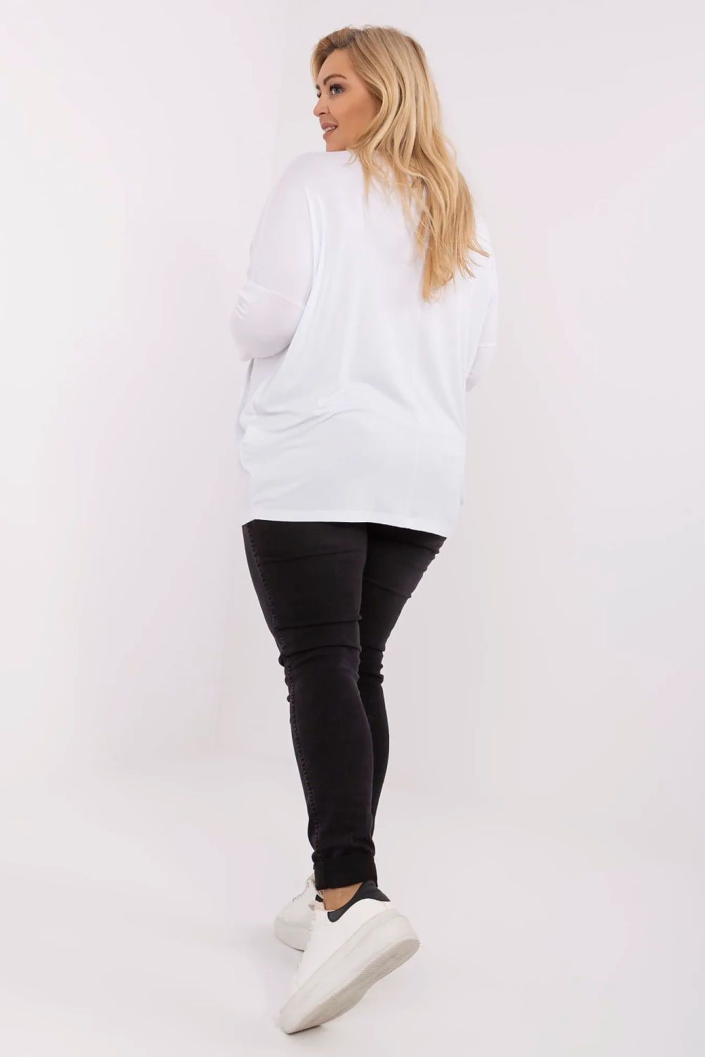 Mulher usando blusa plus size feminina branca com calça preta e tênis branco vista de costas