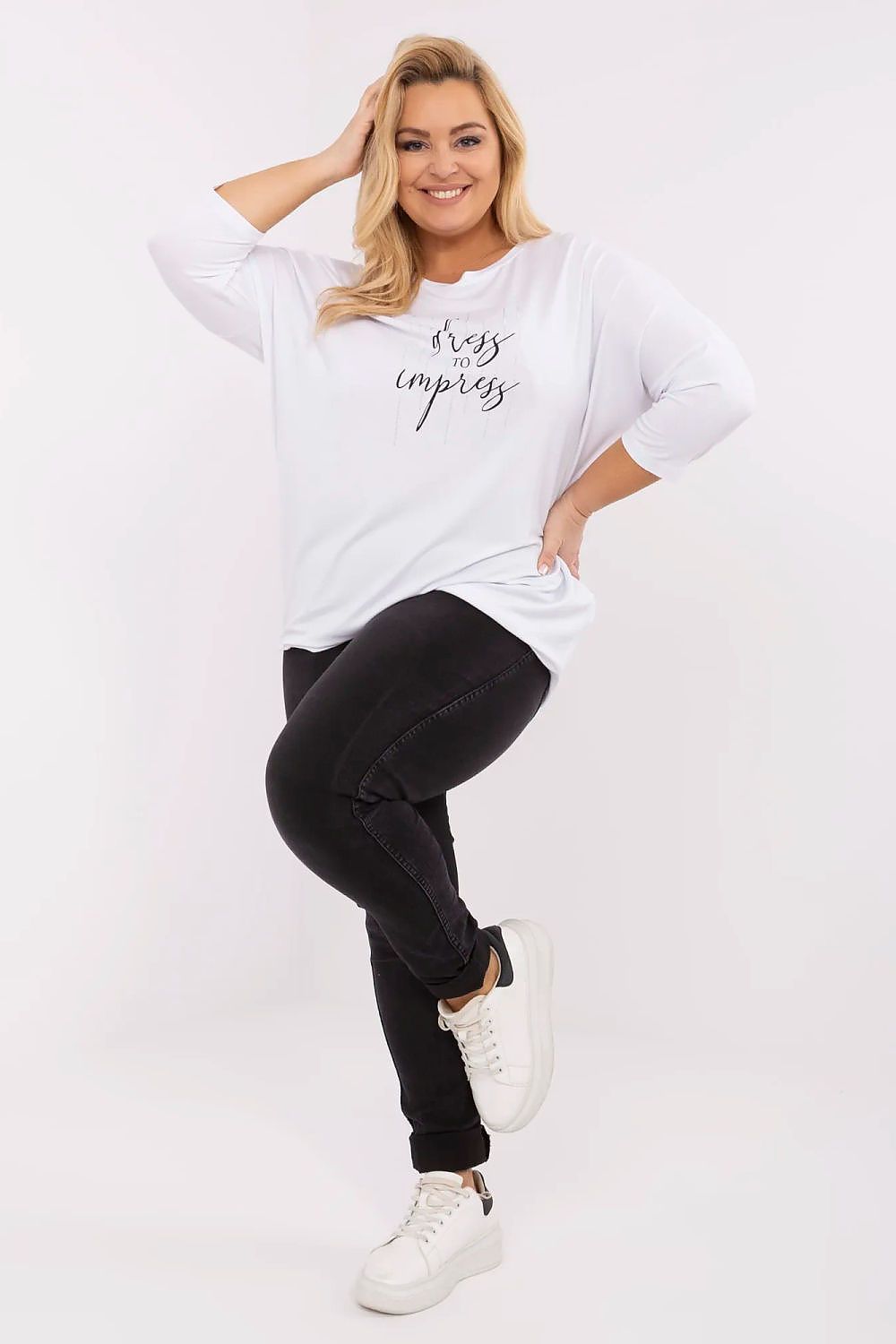 Mulher usando blusa plus size feminina branca com frase e calça preta, com tênis branco