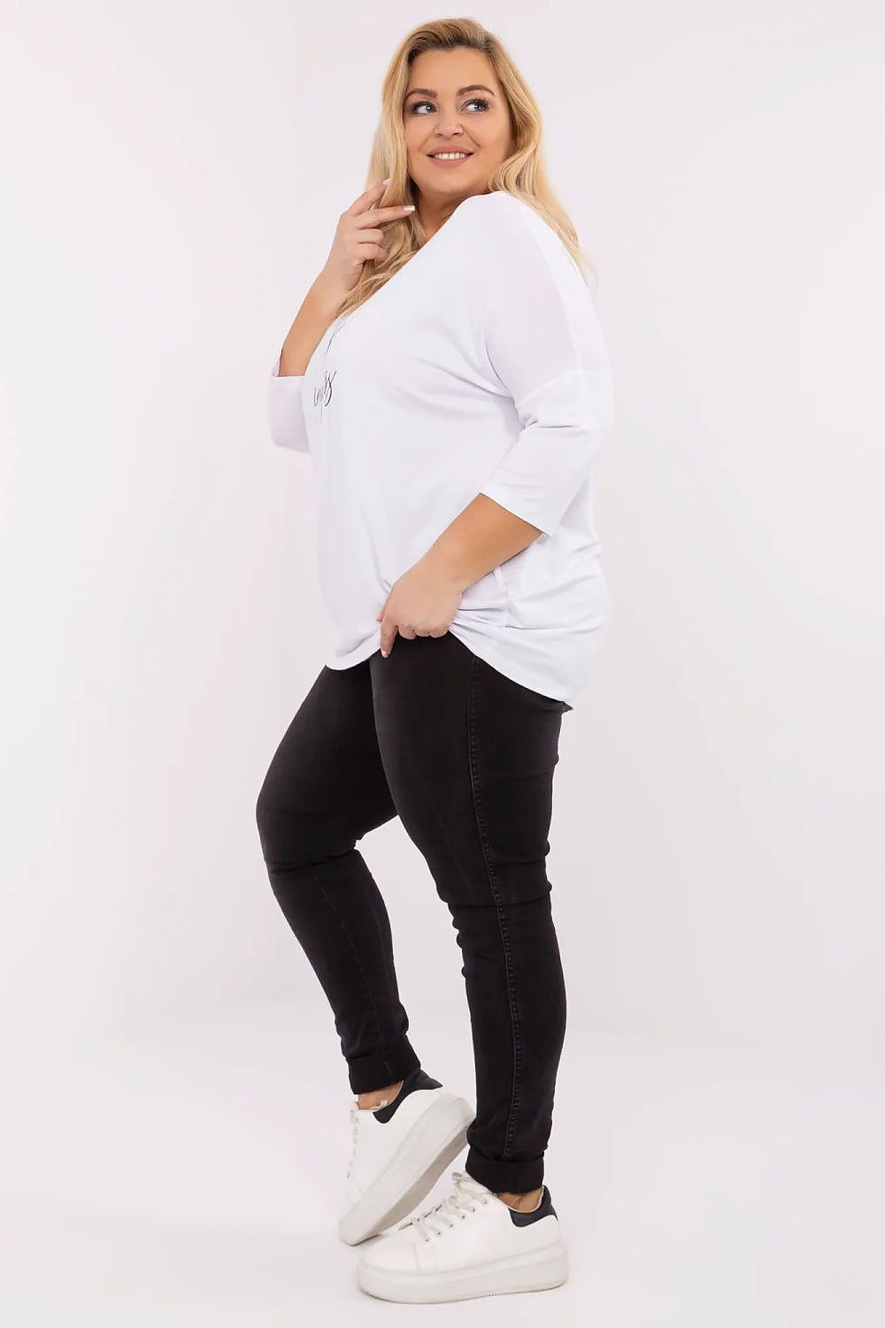 Mulher vestindo blusa plus size feminina branca com calça preta e tênis branco