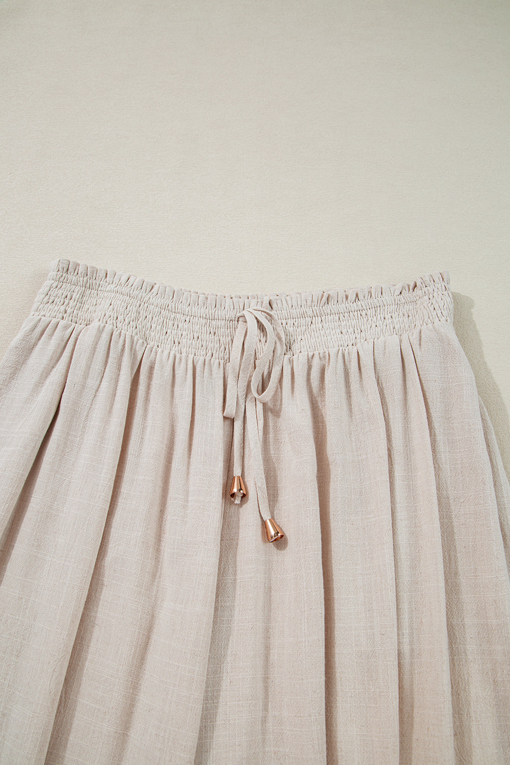 Calça plus size com babado e elástico em tecido leve bege com detalhe de cordão
