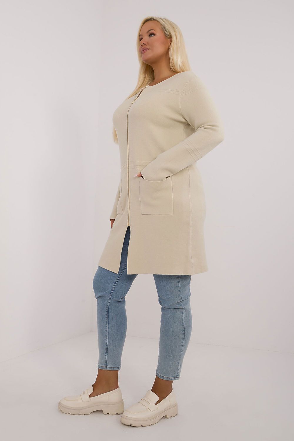 Mulher usando casaco comprido plus size bege com bolso frontal e calça jeans