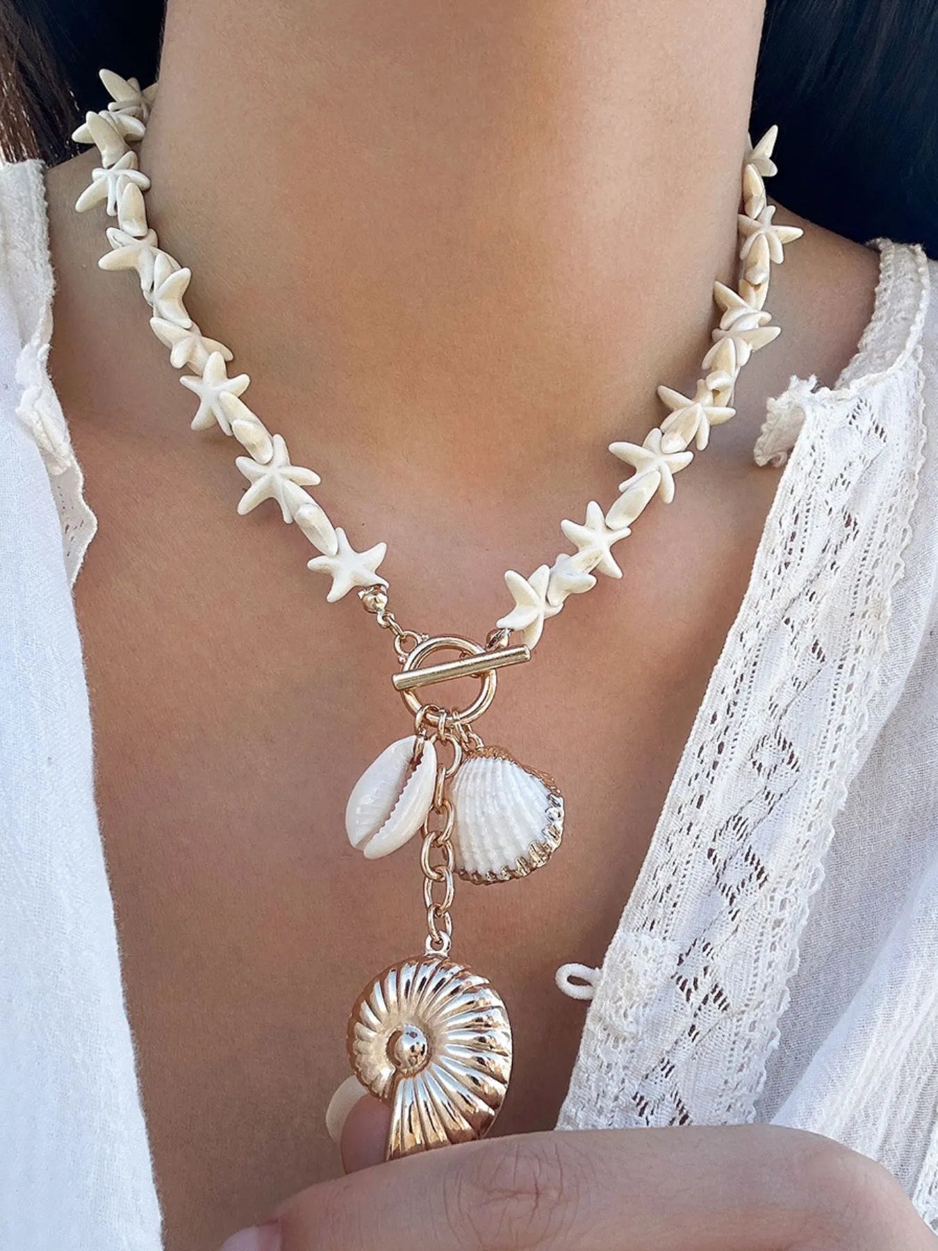 Colar artesanal com pingente de concha feito com detalhes em forma de estrelas do mar em tom creme