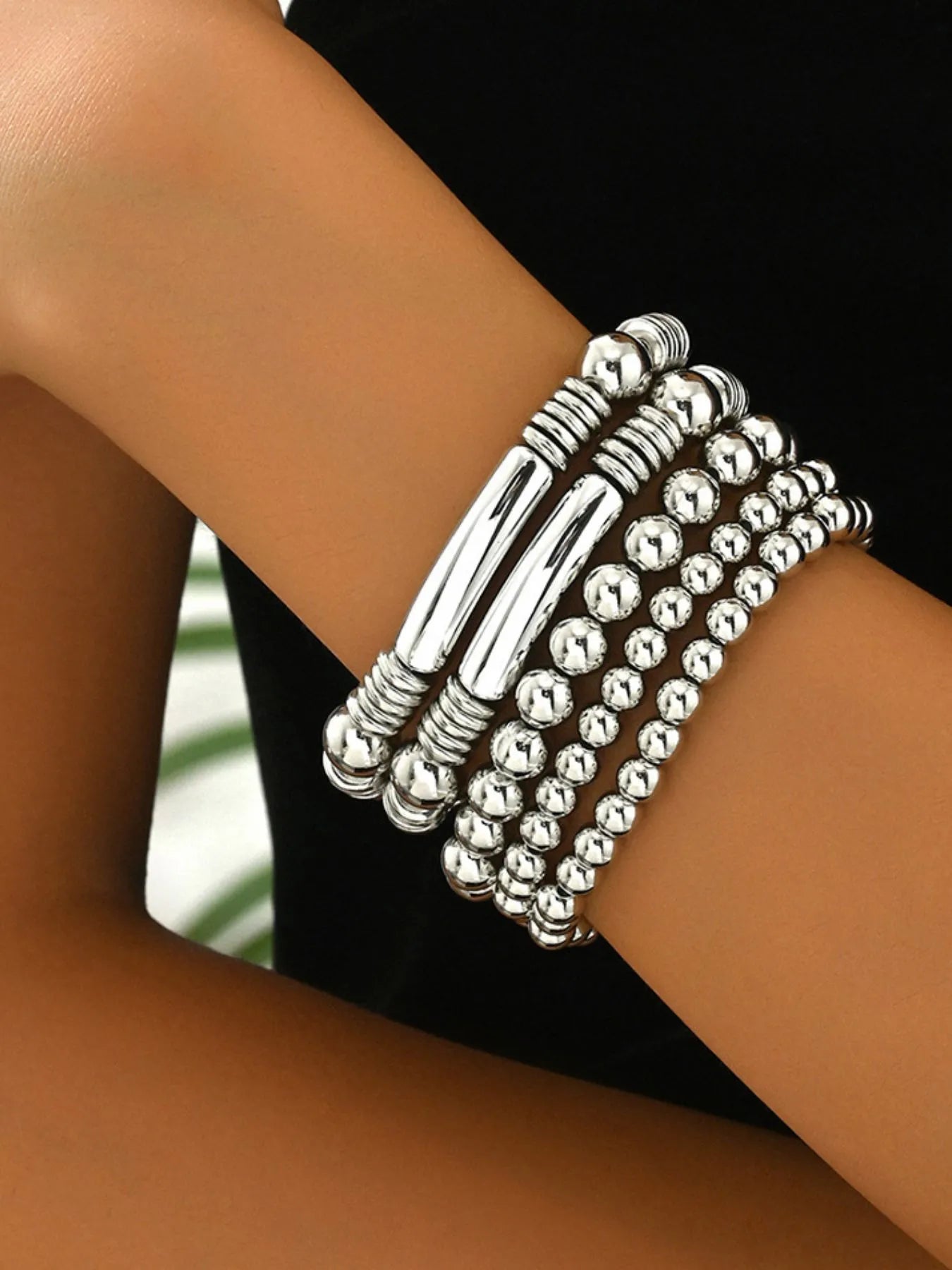 Conjunto de pulseiras delicadas de contas prateadas brilhantes no pulso feminino