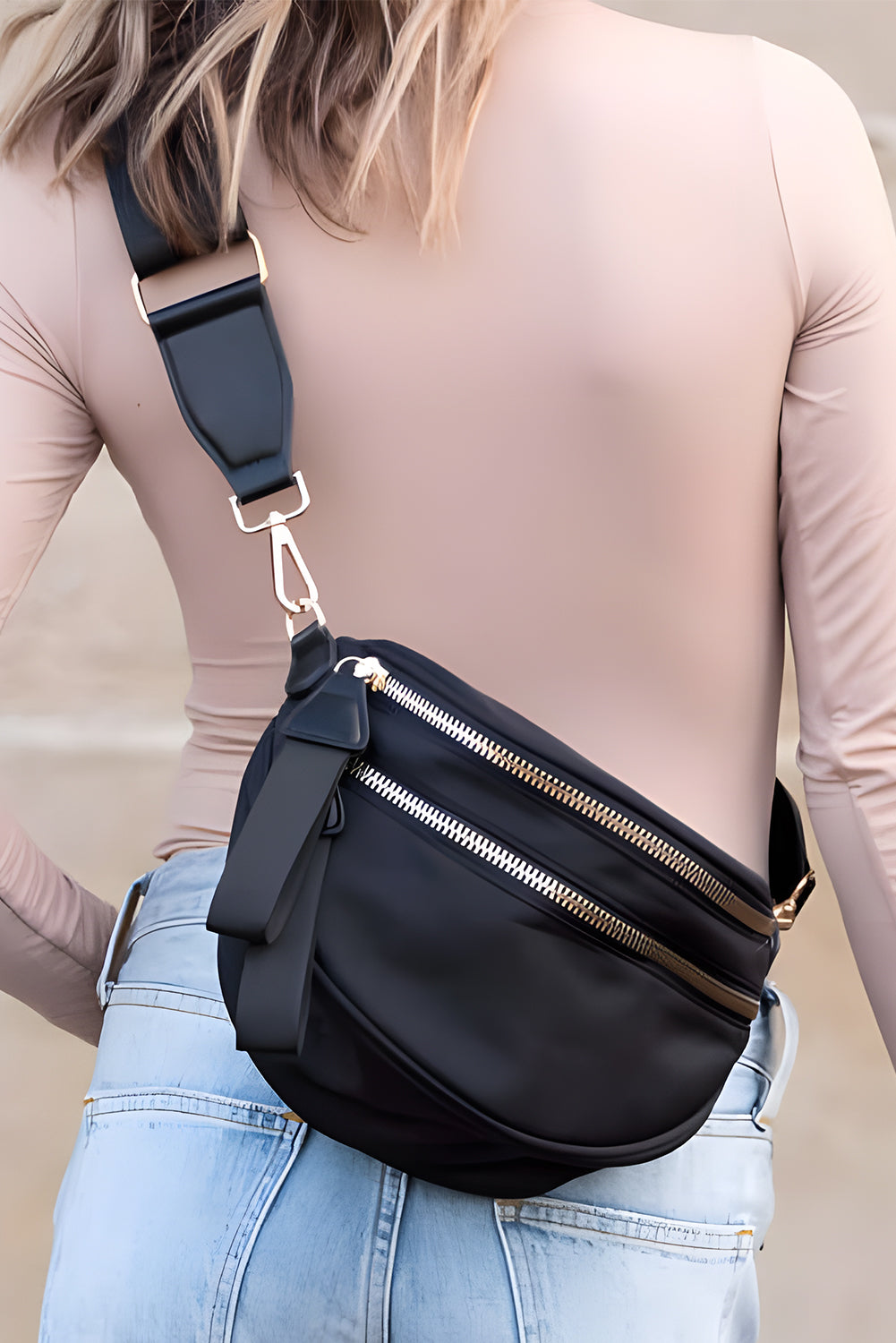 Bolsa transversal feminina com ziper preta usada por mulher com calça jeans azul