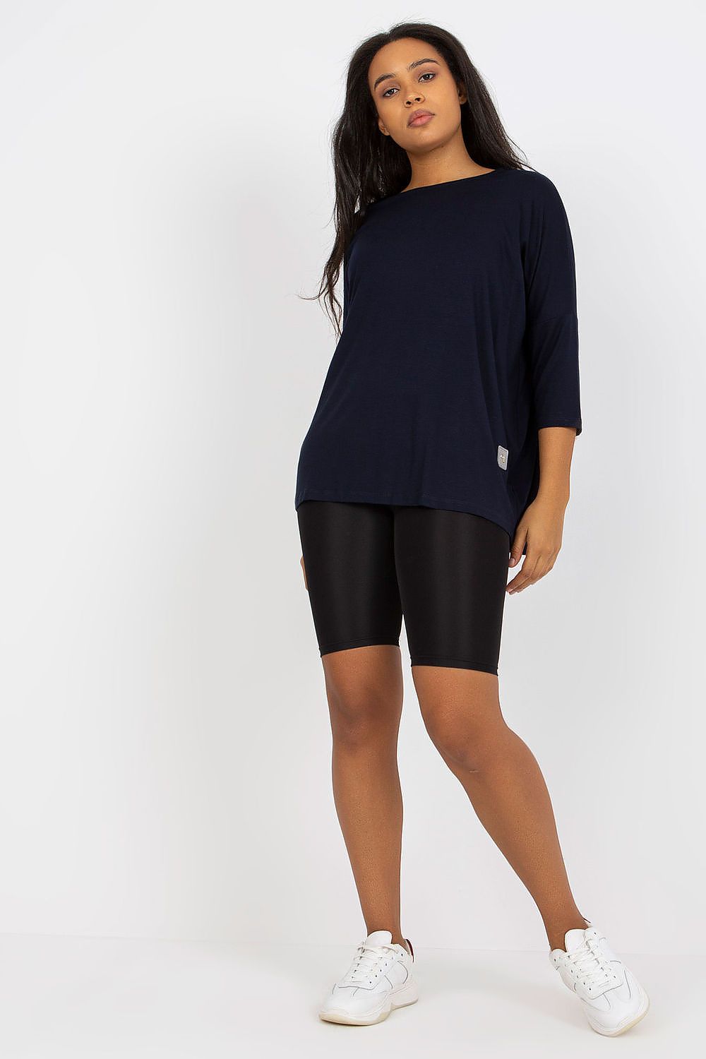 Mulher vestindo blusa tamanho grande moda curvy azul marinho com calça preta e tênis branco
