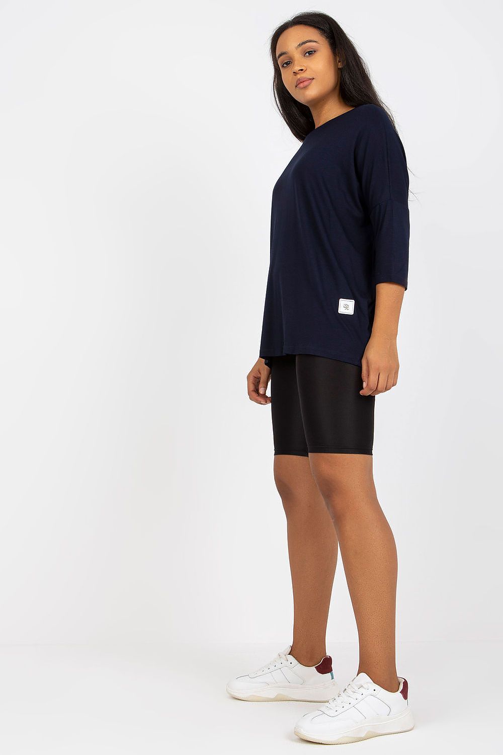 Mulher usando blusa tamanho grande moda curvy azul marinho com shorts pretos e tênis brancos