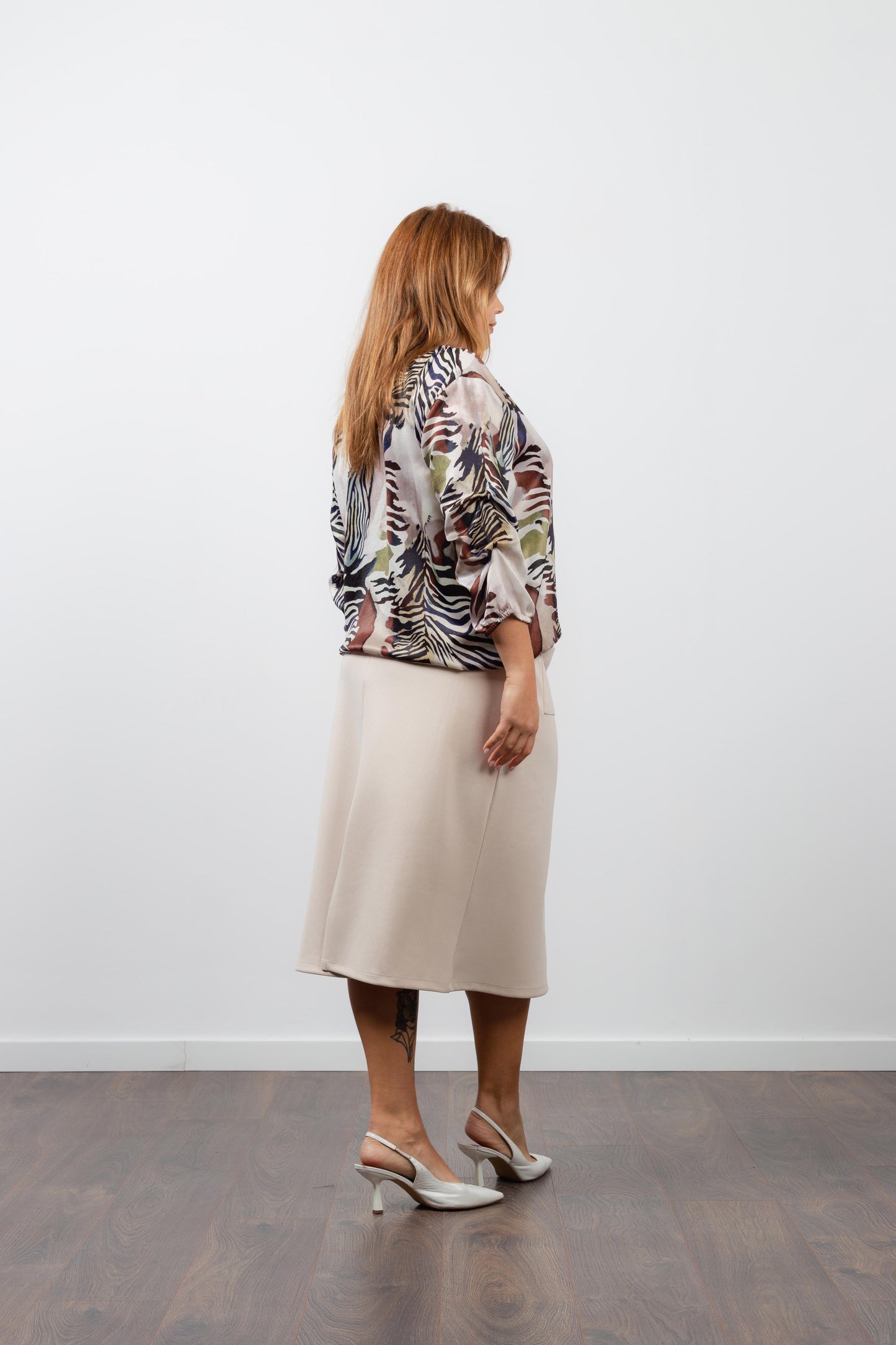 Modelo usando saia midi feminina canelada bege da Curvy com blusa estampada e sapato branco