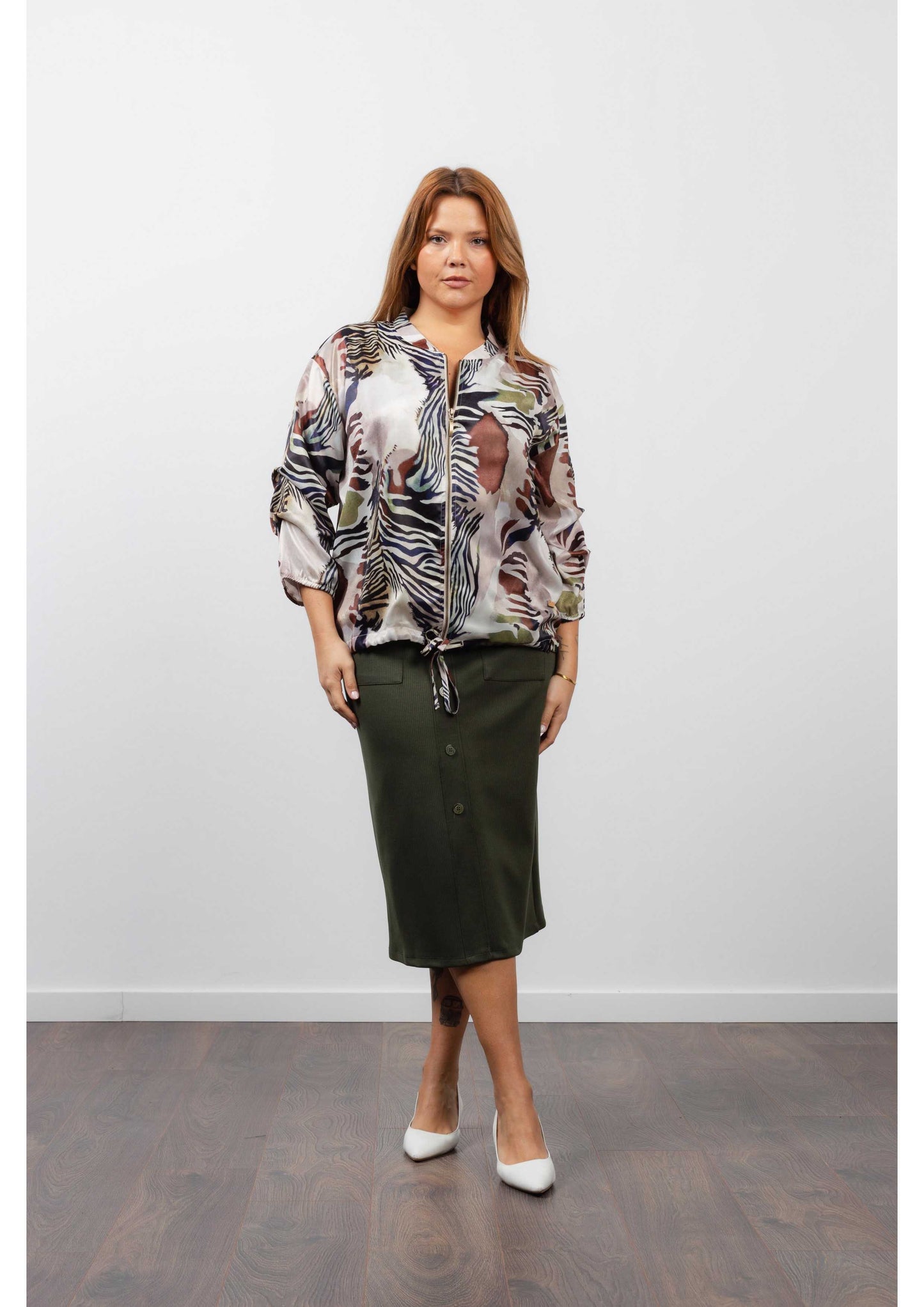 Mulher usando saia midi feminina canelada verde com blusa estampada e salto branco