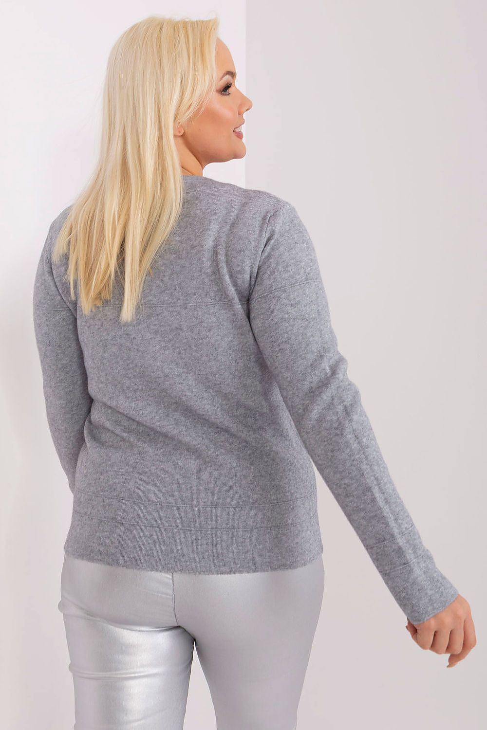 Mulher loira vestindo sweater cinza tamanho grande visto de costas com calça prata