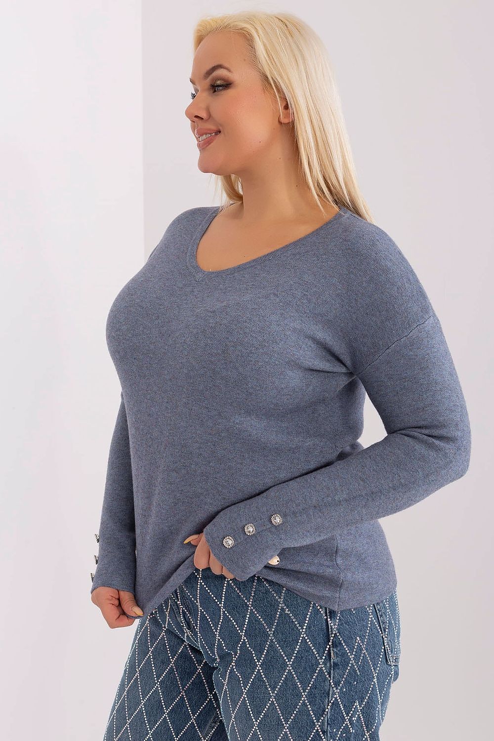 Mulher usando sweater plus size elegante cinza com botões prateados na manga e calça jeans estampada