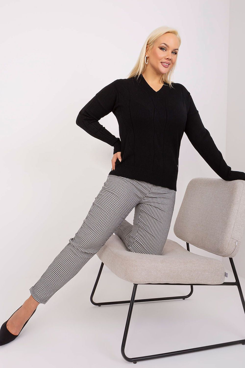 Mulher usando sweater plus size para mulheres preto com calça xadrez e salto preto