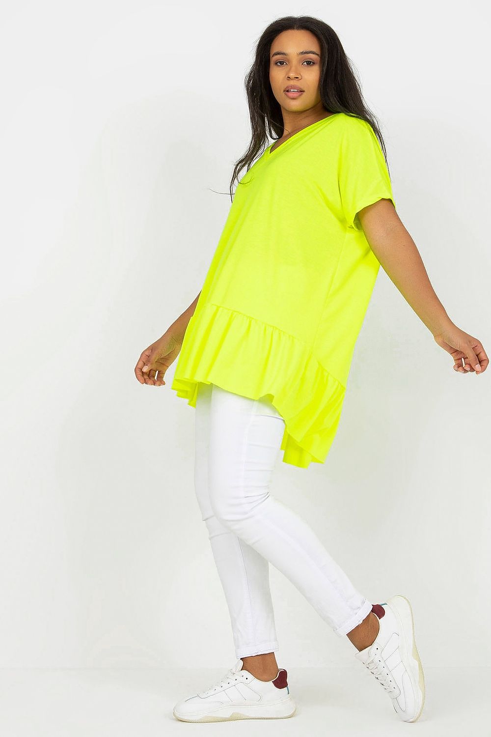 Mulher usando túnica longa plus size neon amarela com calça branca