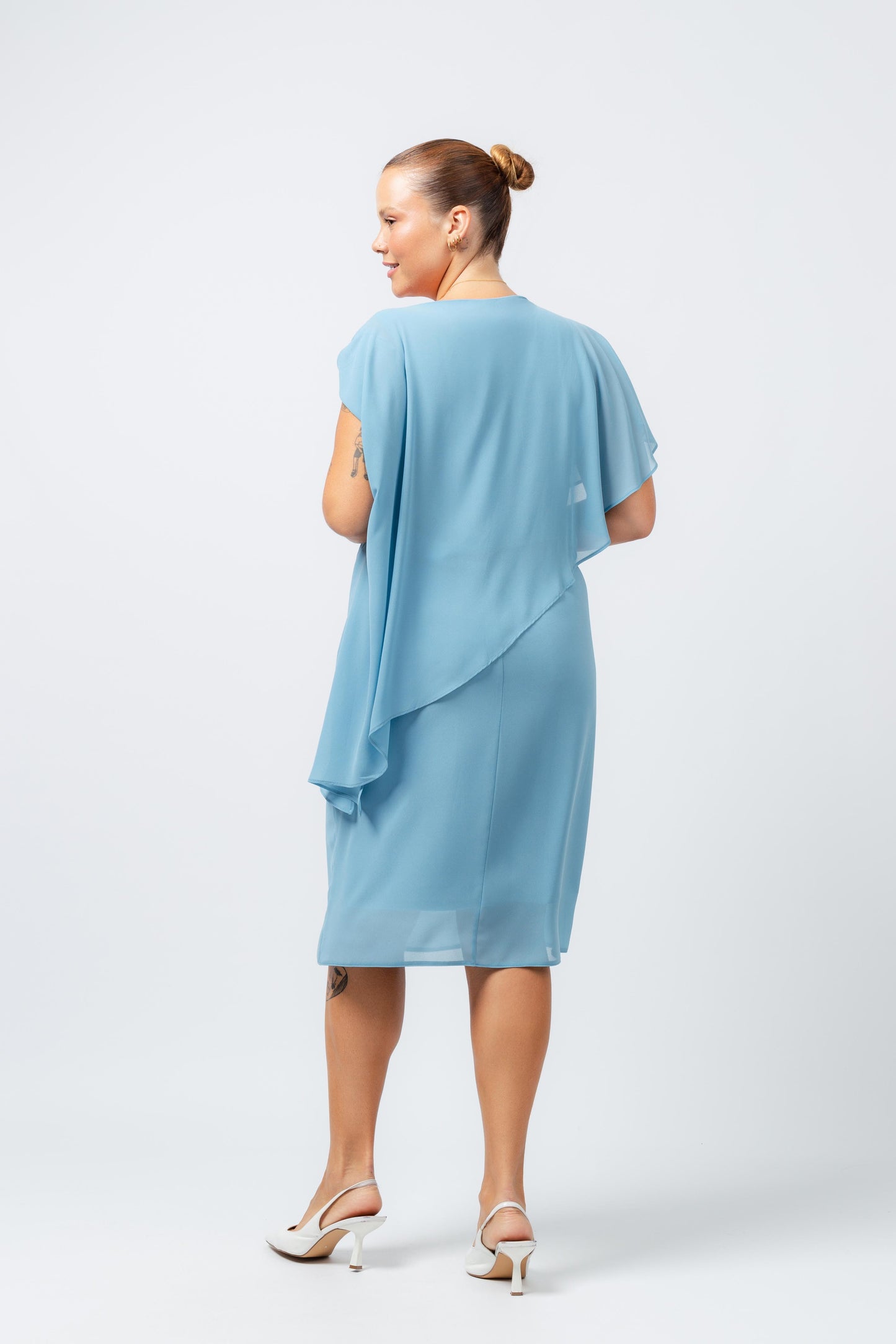 Vestido elegante com capa sobreposta azul claro da Curvy visto por trás com salto branco