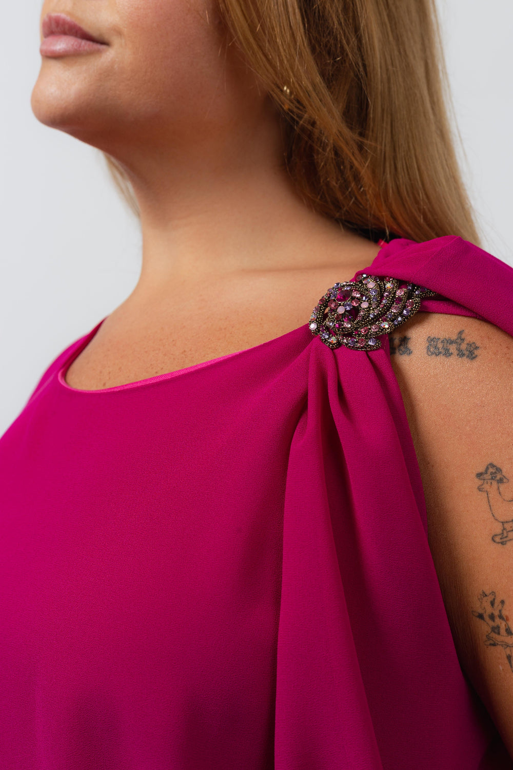 Detalhe do vestido elegante com capa sobreposta Curvy em tom rosa com broche decorativo no ombro