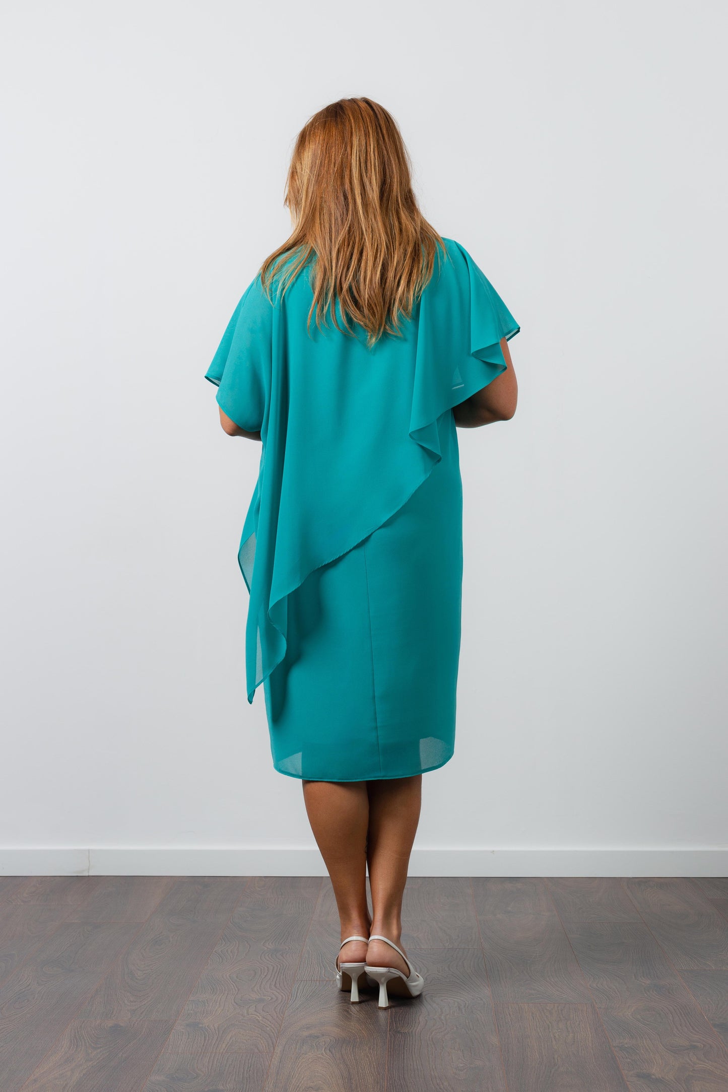 Vestido elegante com capa sobreposta azul da Curvy visto de costas com modelo em pé