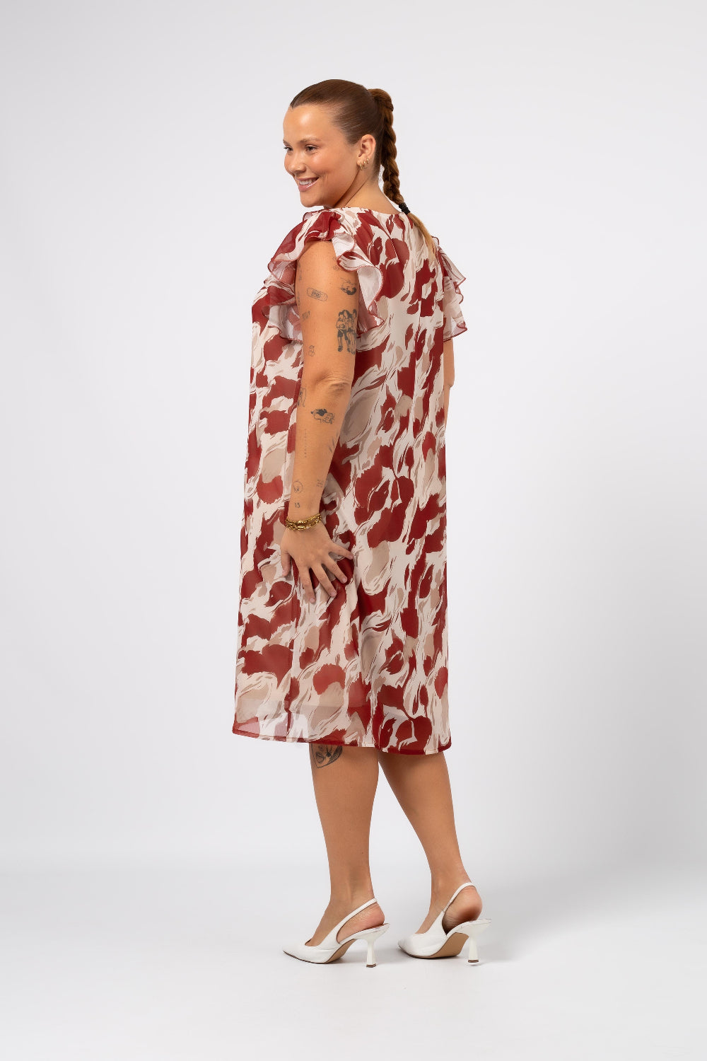 Mulher usando vestido estampado plus size Curvy com estampa vermelha e branca e babados nas mangas