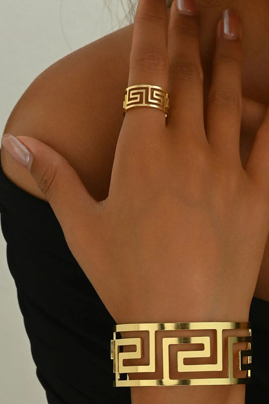 Anel e pulseira estilo grego banhados a ouro com design geométrico usados na mão feminina