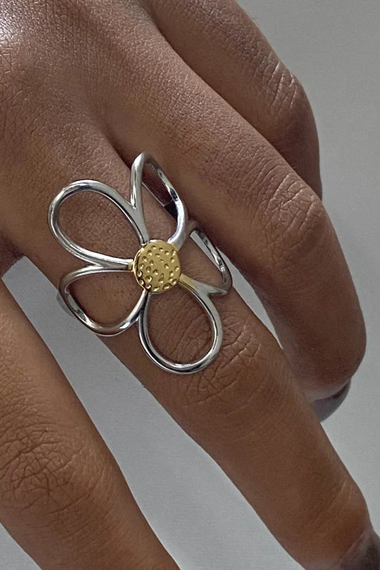 anel margarida bicolor com design flor em prata e centro dourado no dedo