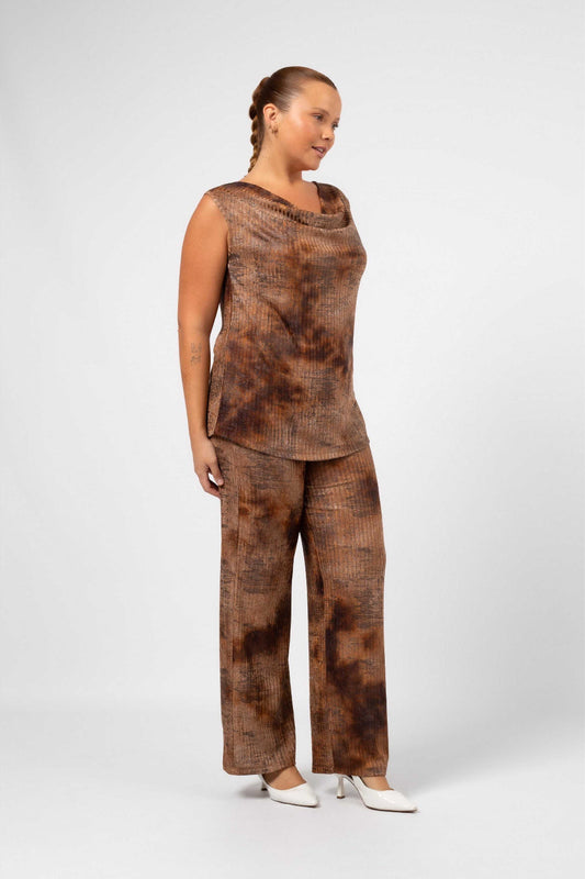Mulher usando calça canelada para mulheres curvy em tom castanho com estampa tie dye e blusa sem mangas combinando