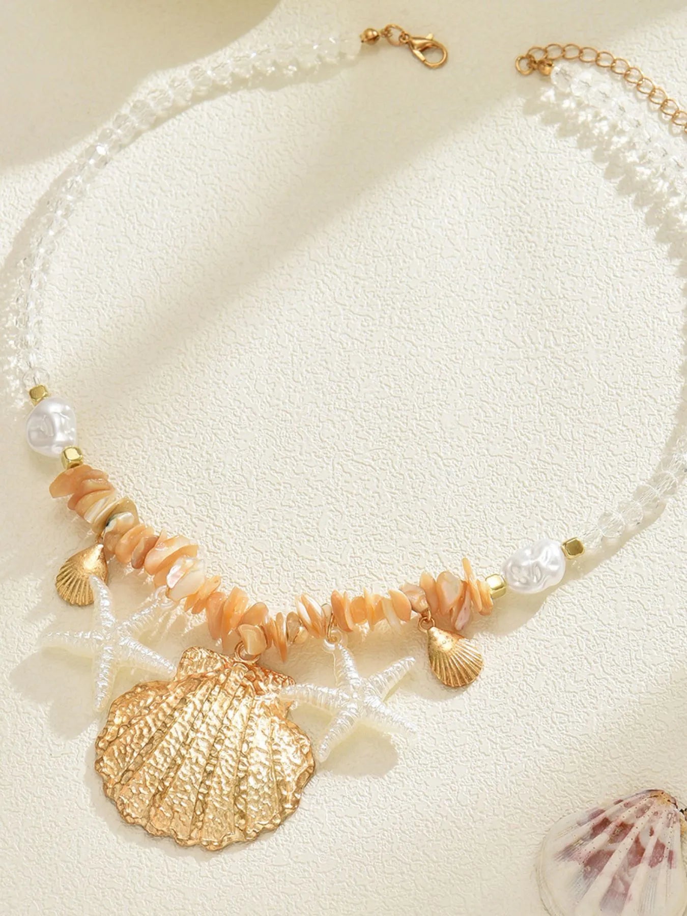 Colar feminino estrela do mar com conchas douradas e pérolas em corrente transparente