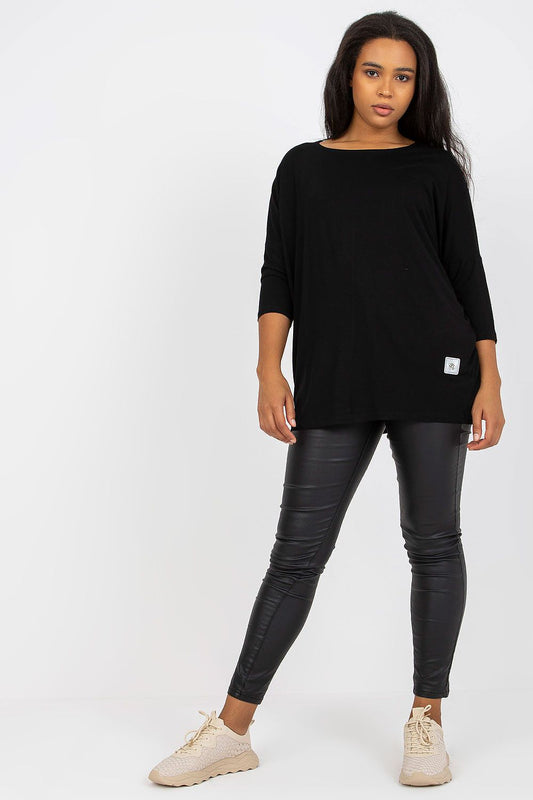 Modelo usando blusa tamanho grande moda curvy preta com calça legging preta e tênis bege
