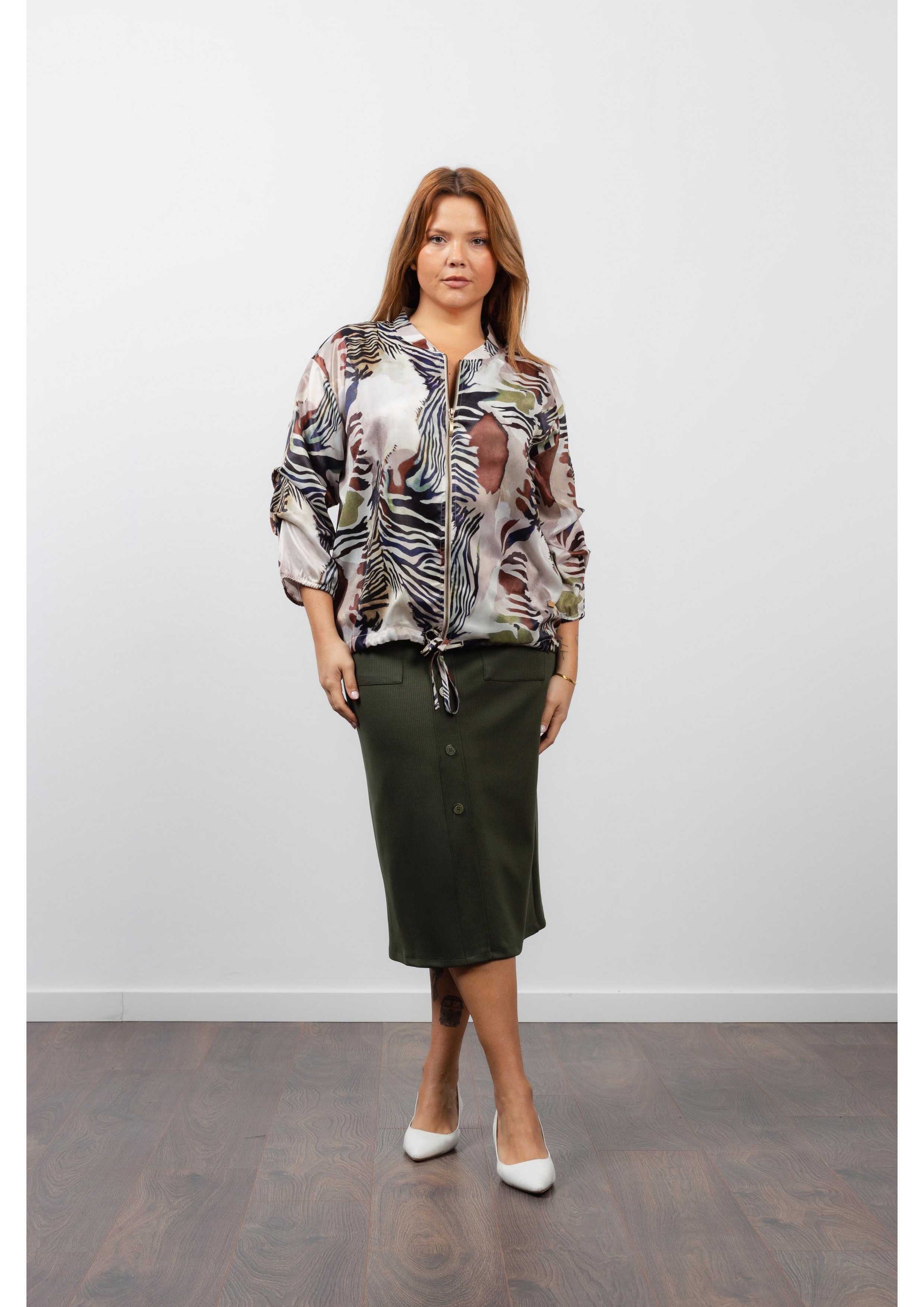 Mulher usando saia midi feminina canelada verde com blusa estampada e salto branco