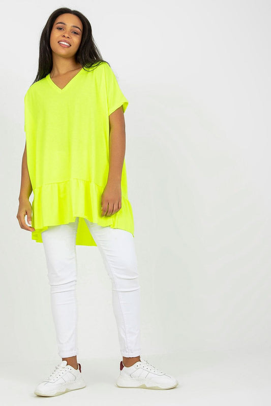 Mulher usando túnica longa plus size neon amarela com calça branca e tênis branco