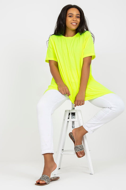 Mulher usando túnica neon plus size manga curta amarelo vibrante com calça branca e sandálias